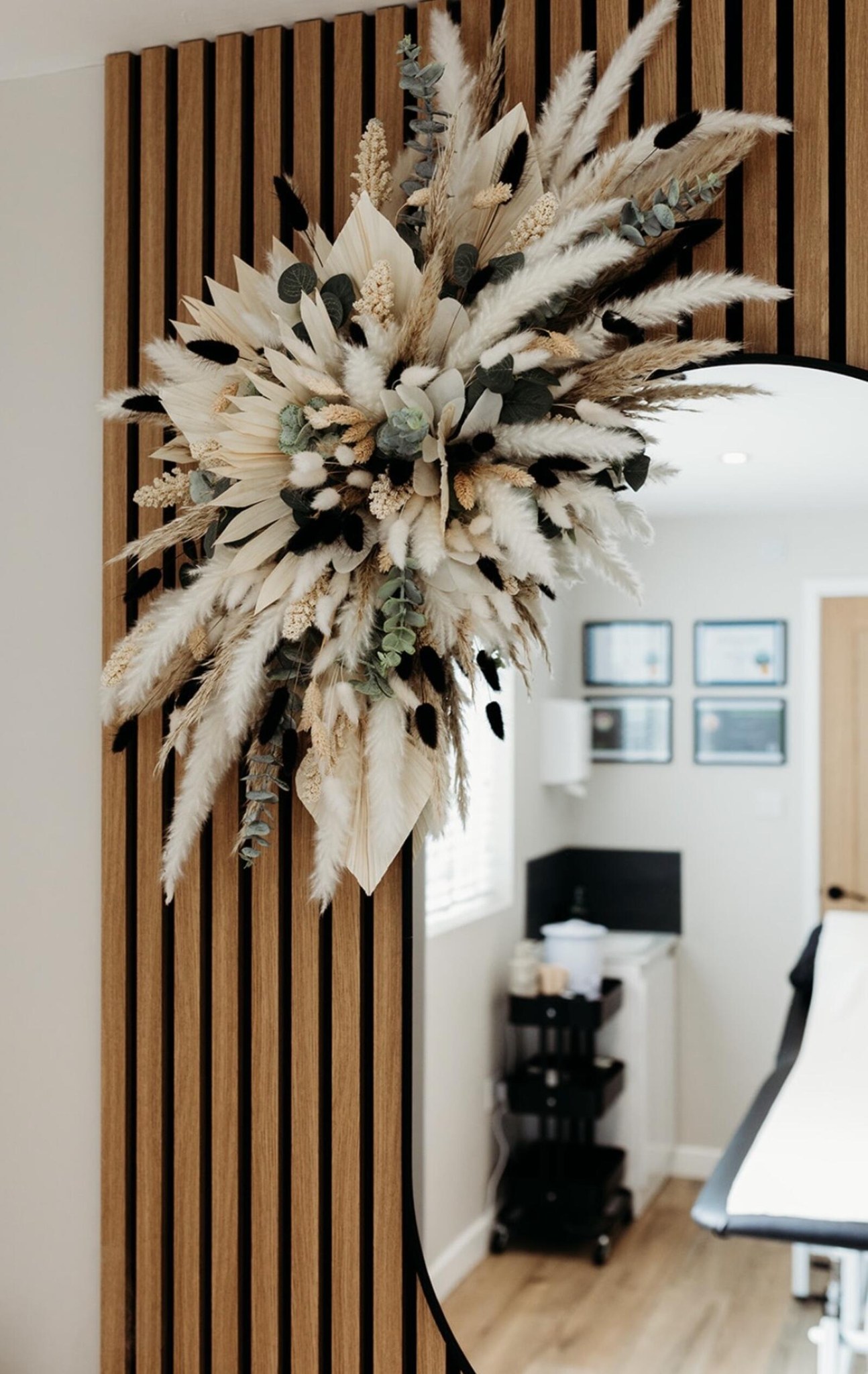 Dried pampas and the round mirror on the oak-slatted wall