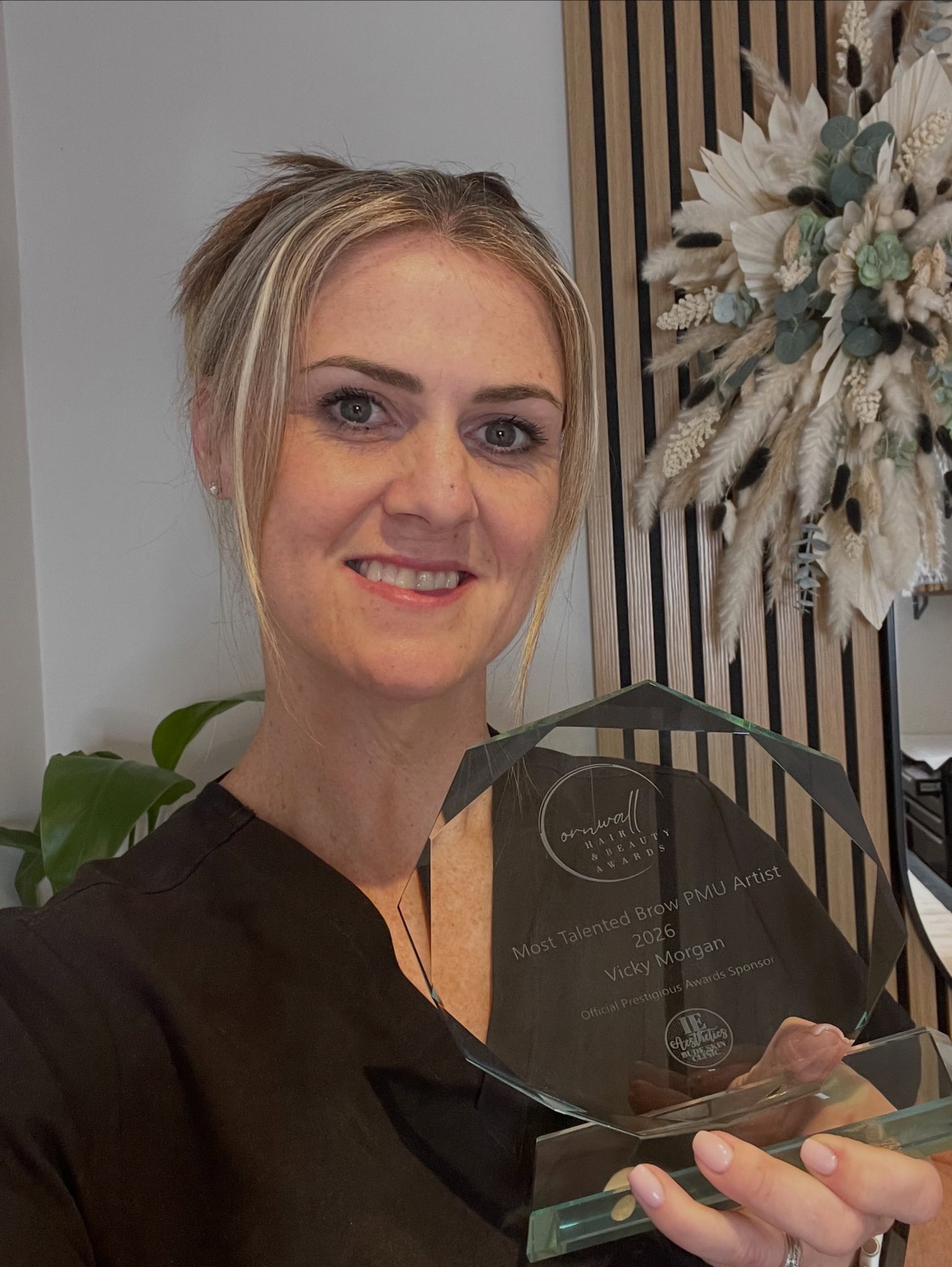 Vicky holding her Most Talented Brow PMU Artist trophy in the clinic